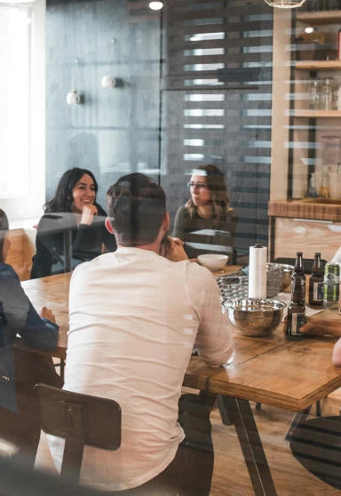Group of people sitting around a wooden table having a conversation in a modern office.