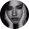 Black and white close-up of a contemplative young woman resting her face in her hands.