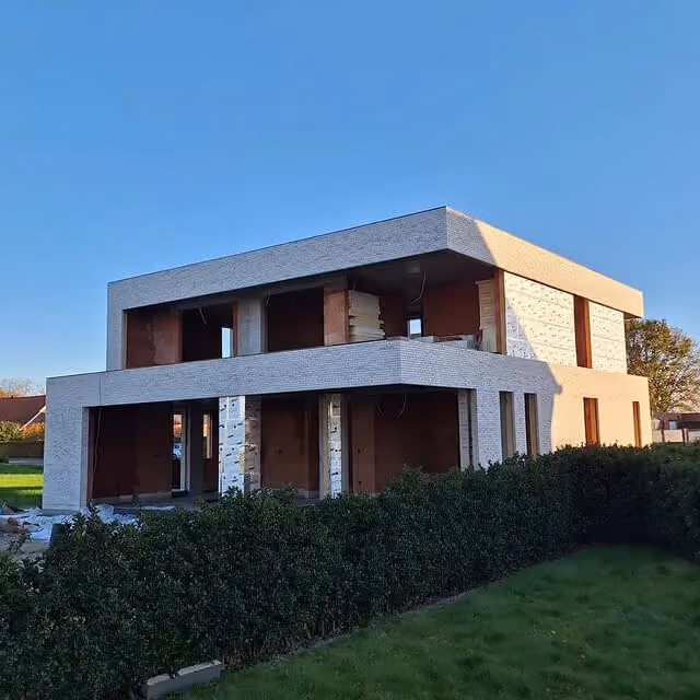Nieuwbouwwoning in ruwbouwfase met witte gevelsteen en nog niet afgewerkte raamopeningen