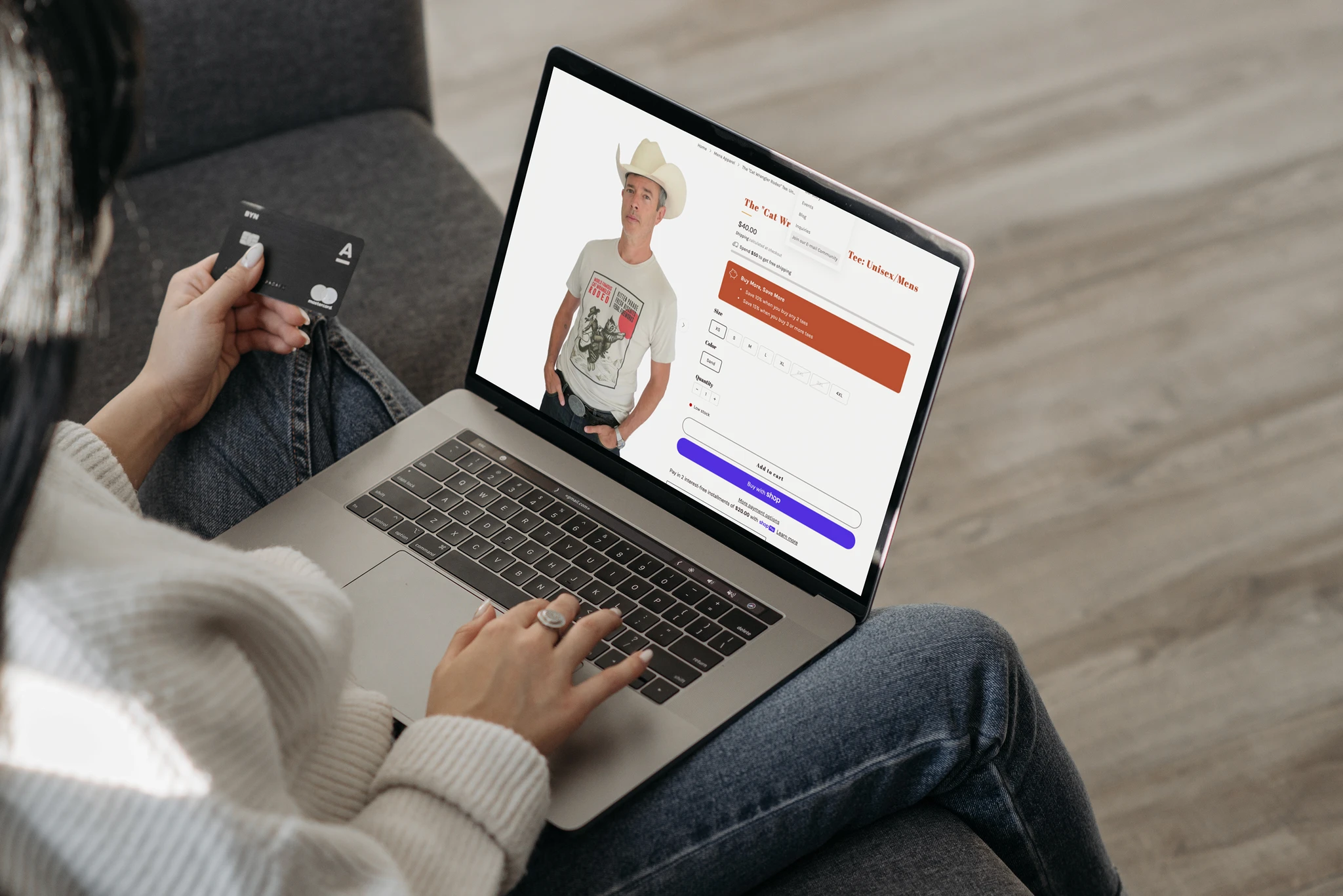 Person sitting with laptop open on lap shopping on pet rodeo with a credit card in hand
