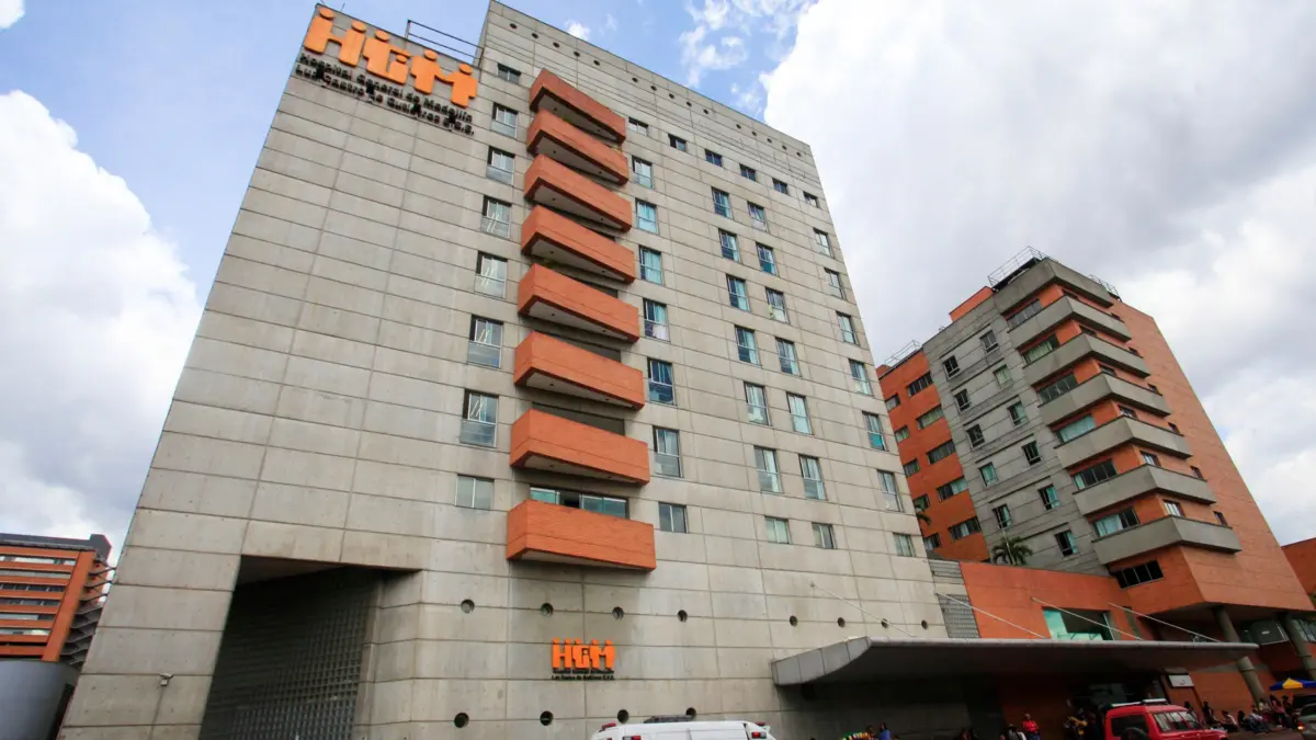 Hospital General de Medellín con ambulancias frente al edificio bajo cielo nublado.