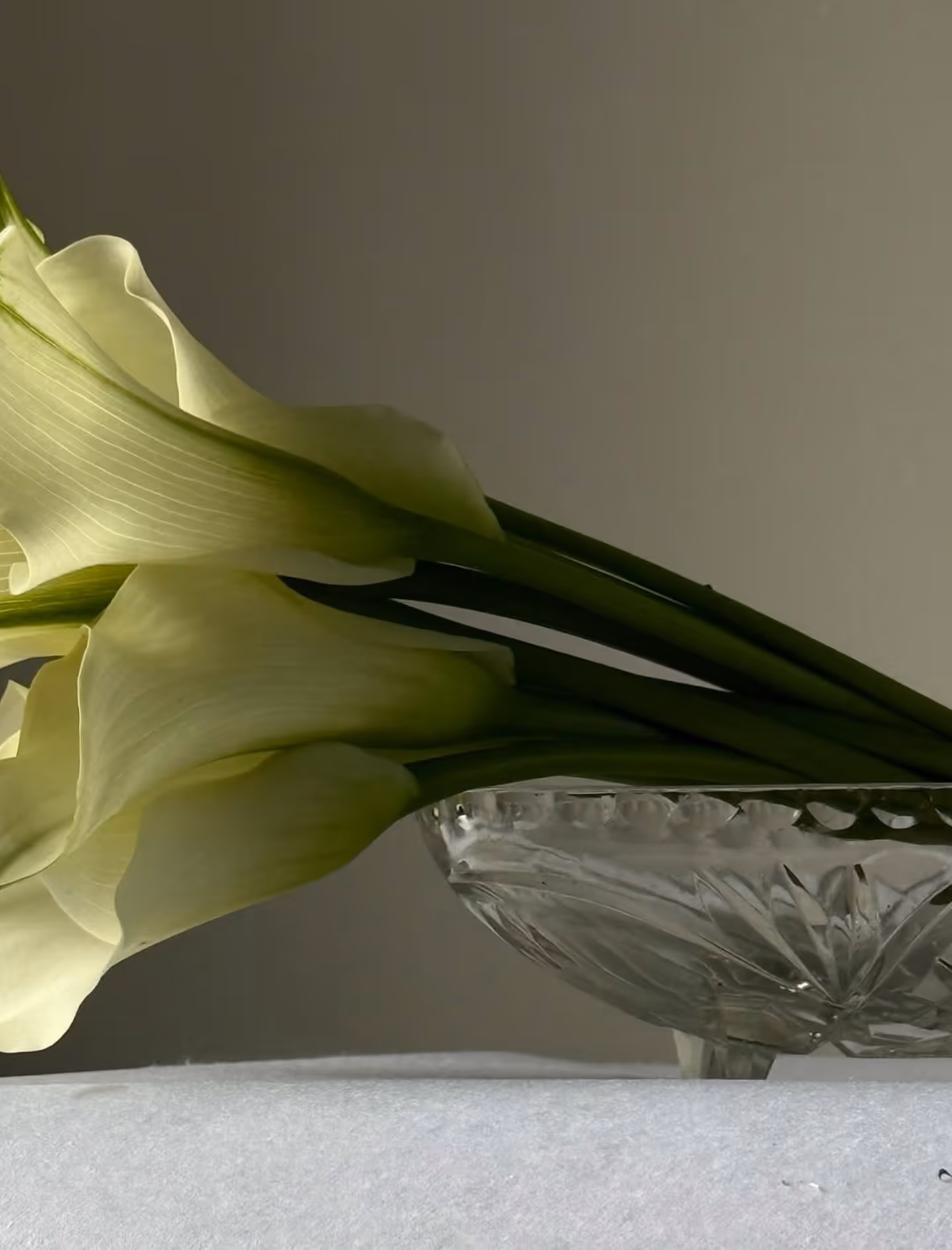Floral arrangement with pink peonies and white flowers in silver vase on white pedestal.