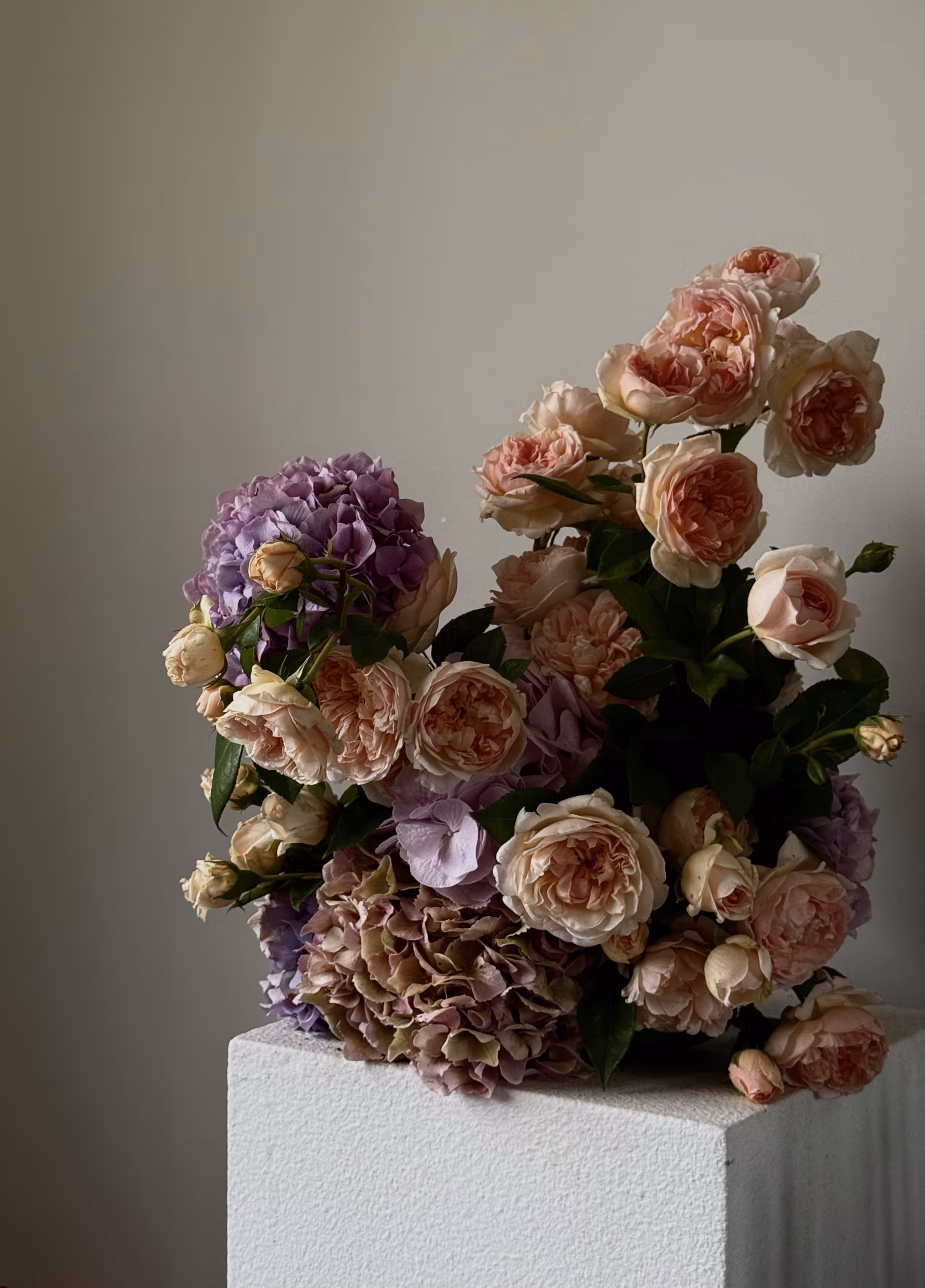Clusters of delicate pink tulips with green leaves draped over a shiny crinkled metallic surface.