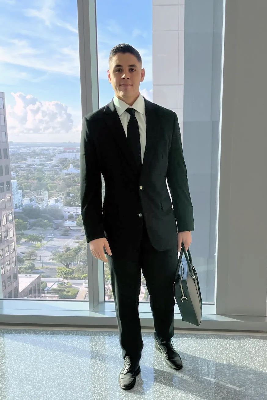 Attorney Edon Saiyag standing by a high-rise window with a briefcase