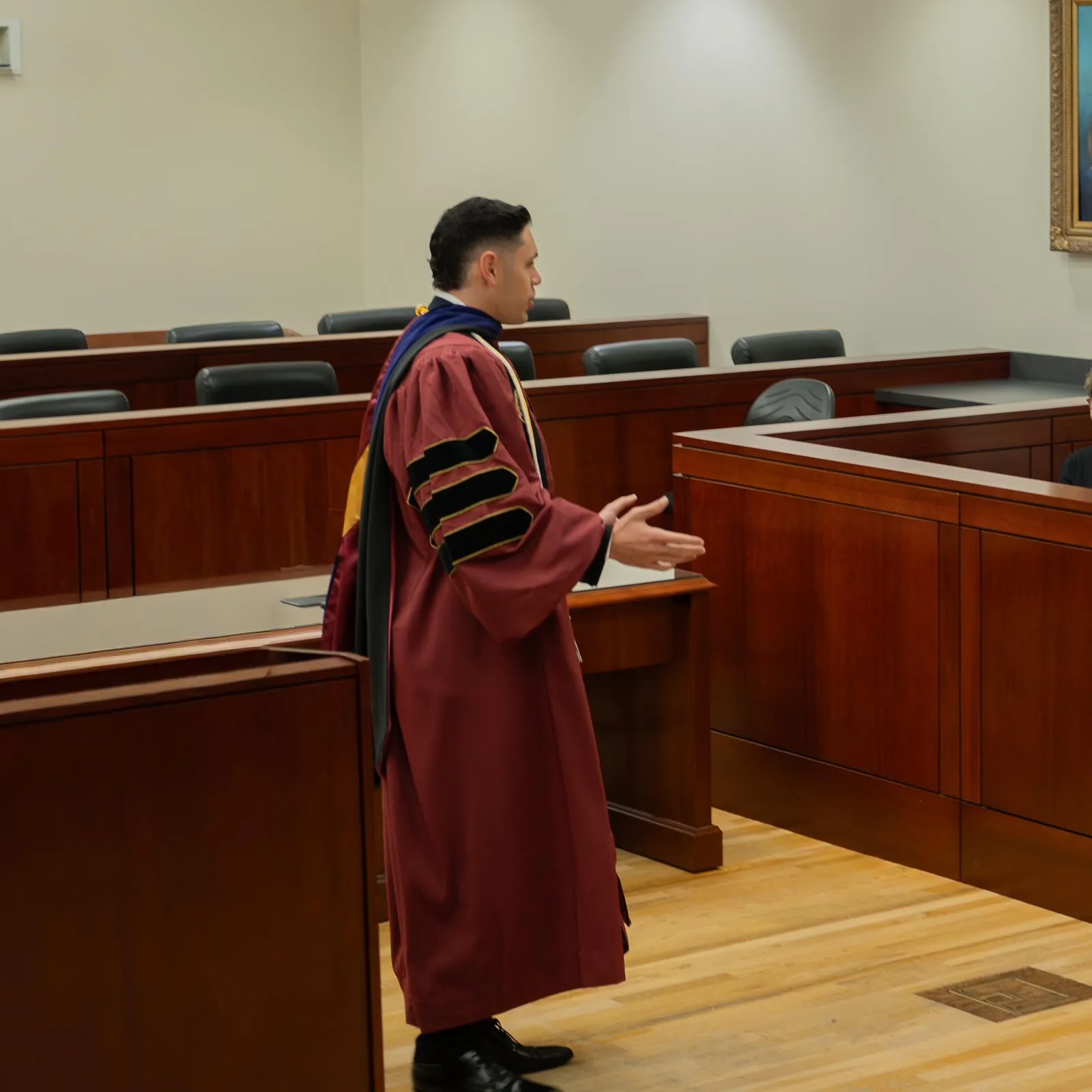 Edon Saiyag speaking in a courtroom while wearing academic regalia