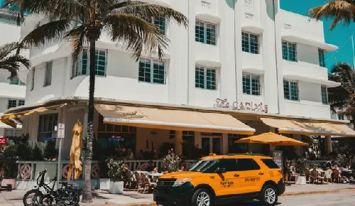 Art Deco building and yellow taxi on a palm-lined Miami street