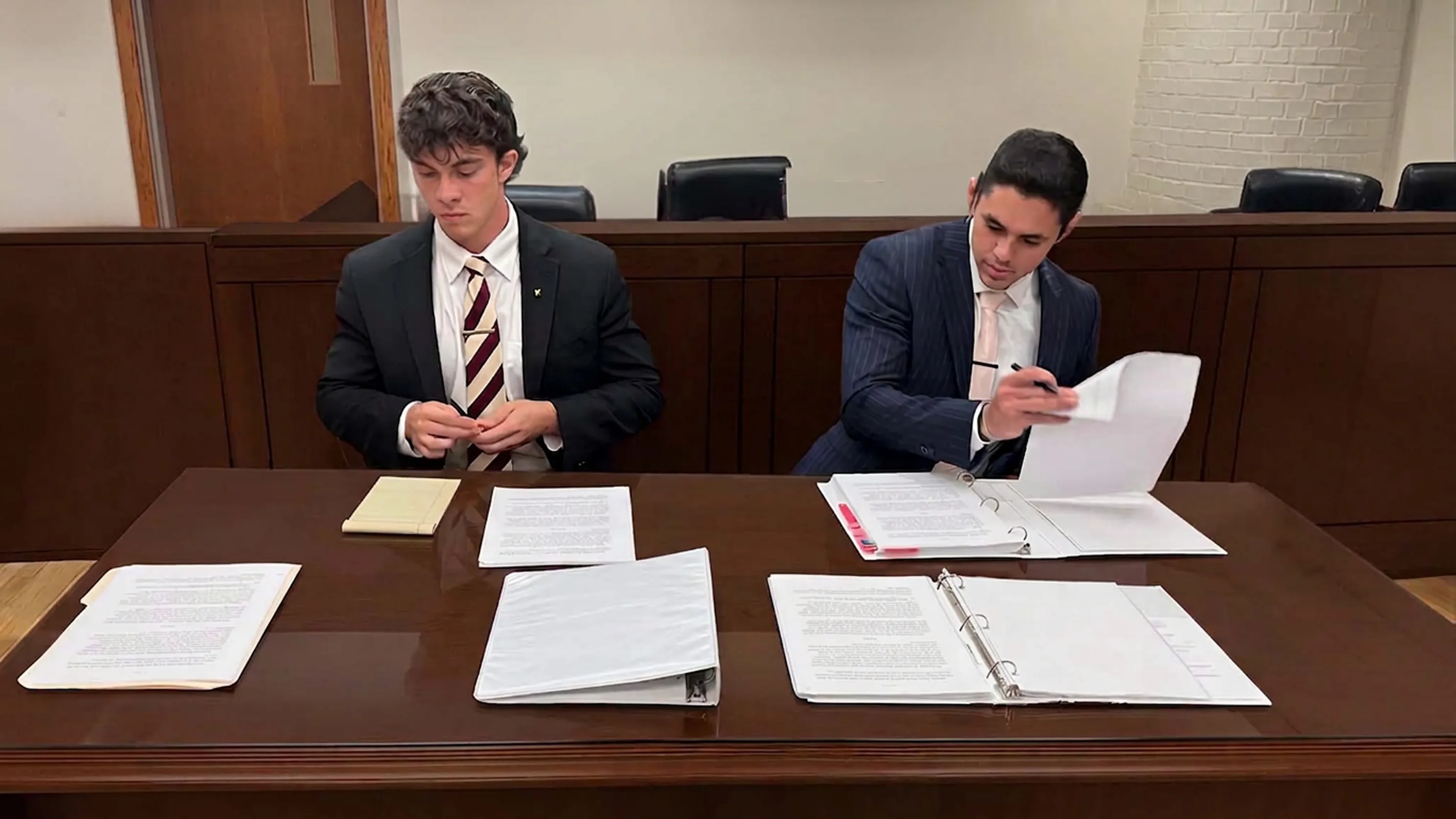 Edon Saiyag and another man reviewing documents at a courtroom counsel table