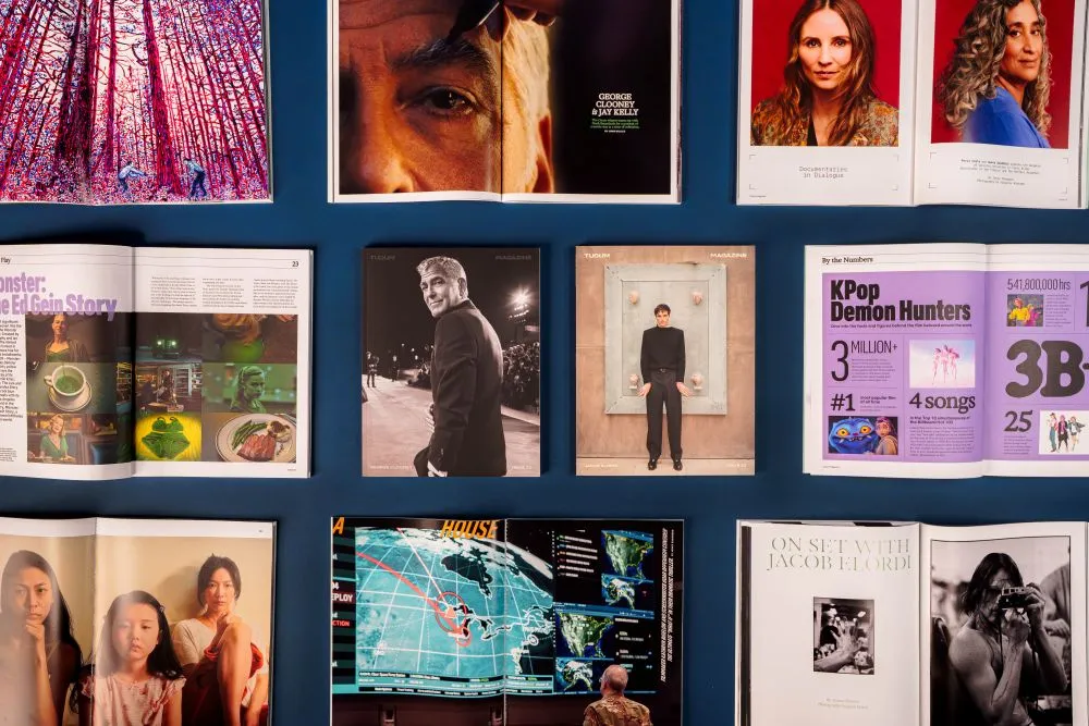 Overhead view of multiple open magazines displaying portraits, articles, and a map on a dark blue surface.