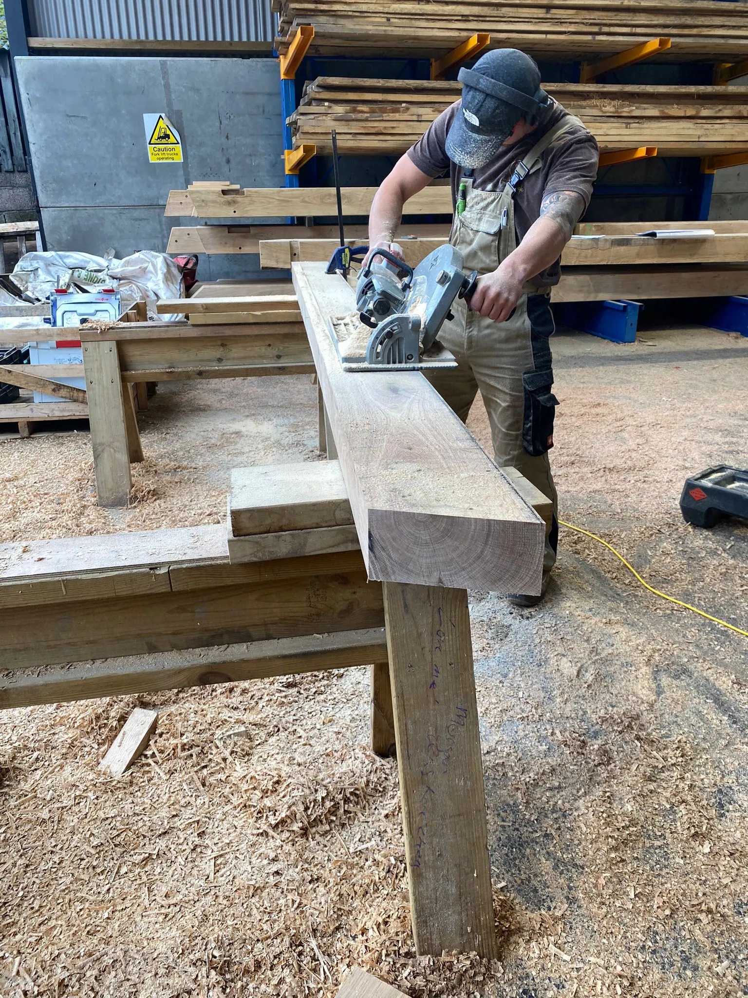 A carpenter cutting a post on the workshop trestles