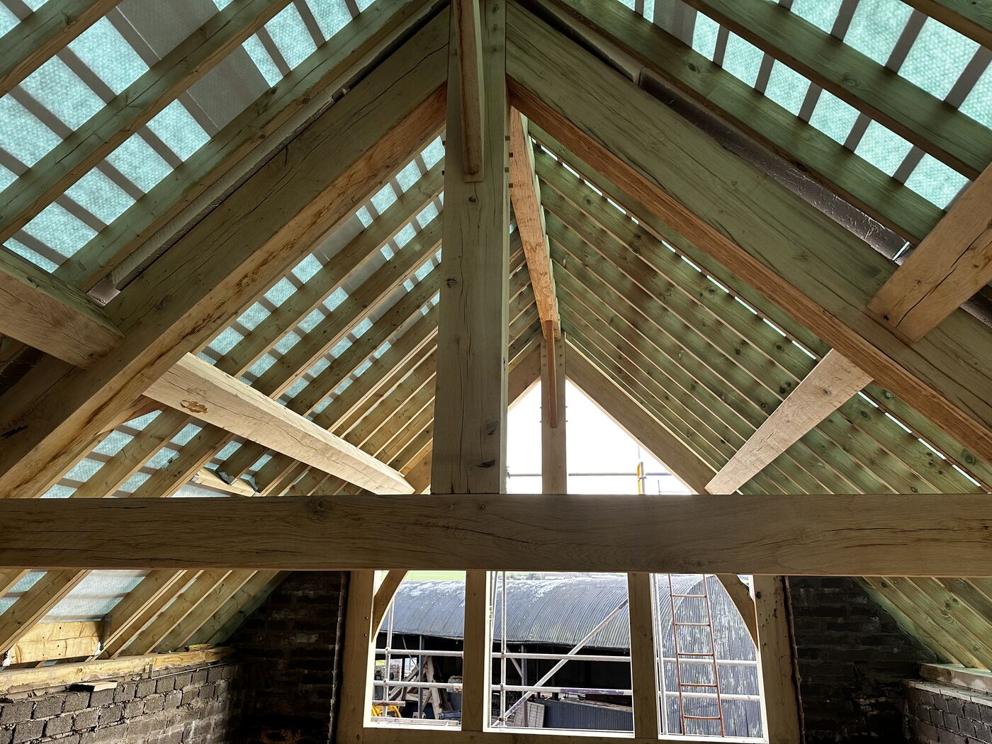 Green oak roof trusses and a glazed oak gable screen inside the barn next to the Foxtail Oak workshop near Abergavenny.