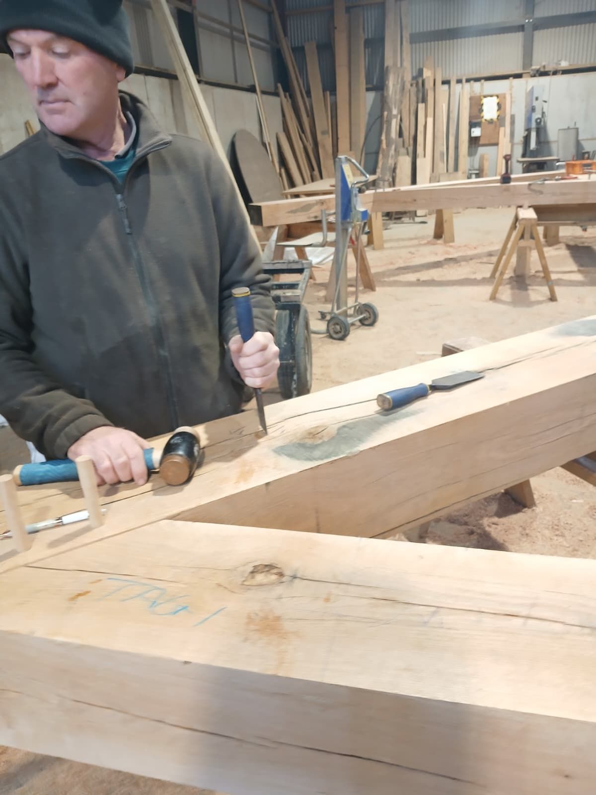 A Foxtail Oak carpenter cutting a joint by hand with a chisel and mallet in the workshop near Abergavenny.