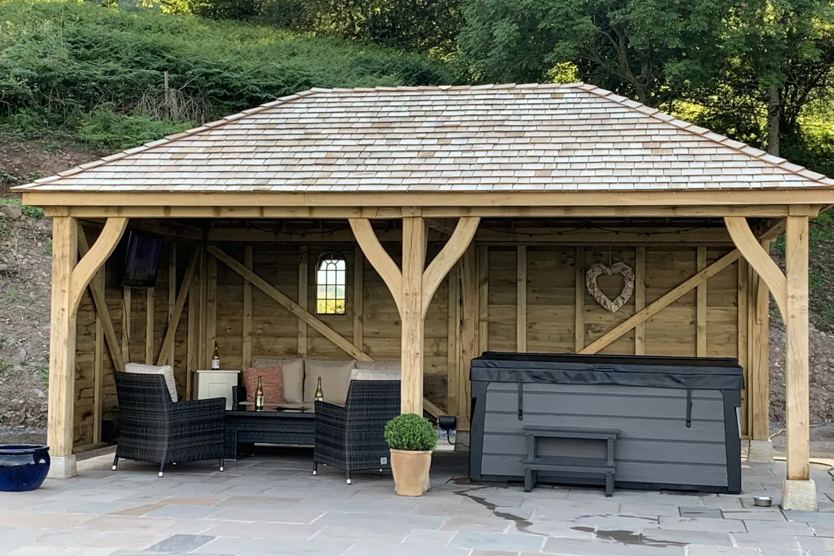 Oak gazebo with a cedar shingle hipped roof over a hot tub at Gilwern