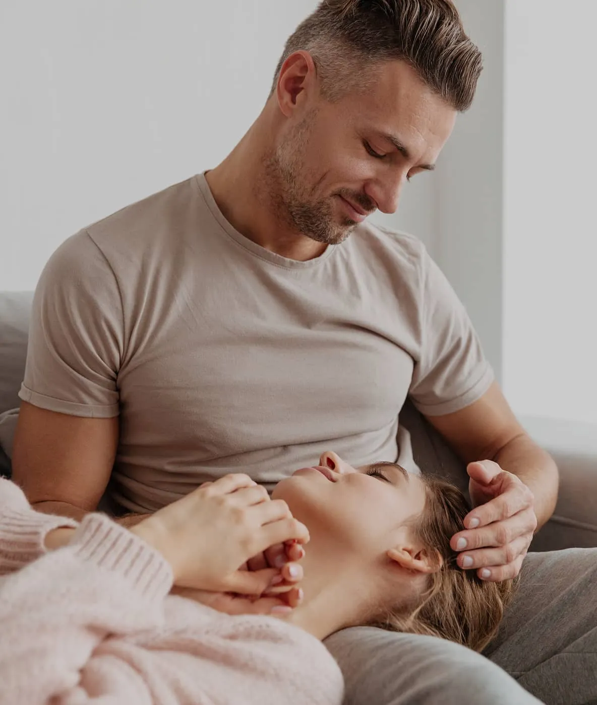 Man gently cradling woman’s head as she rests on his lap looking up at him affectionately.