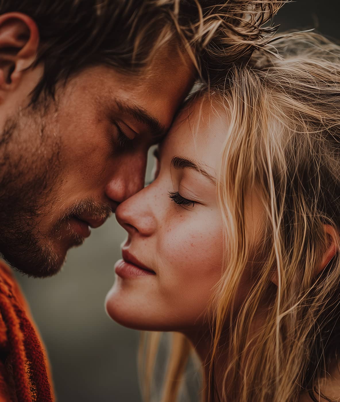 Close-up of a man and woman touching foreheads with eyes closed in an intimate moment.