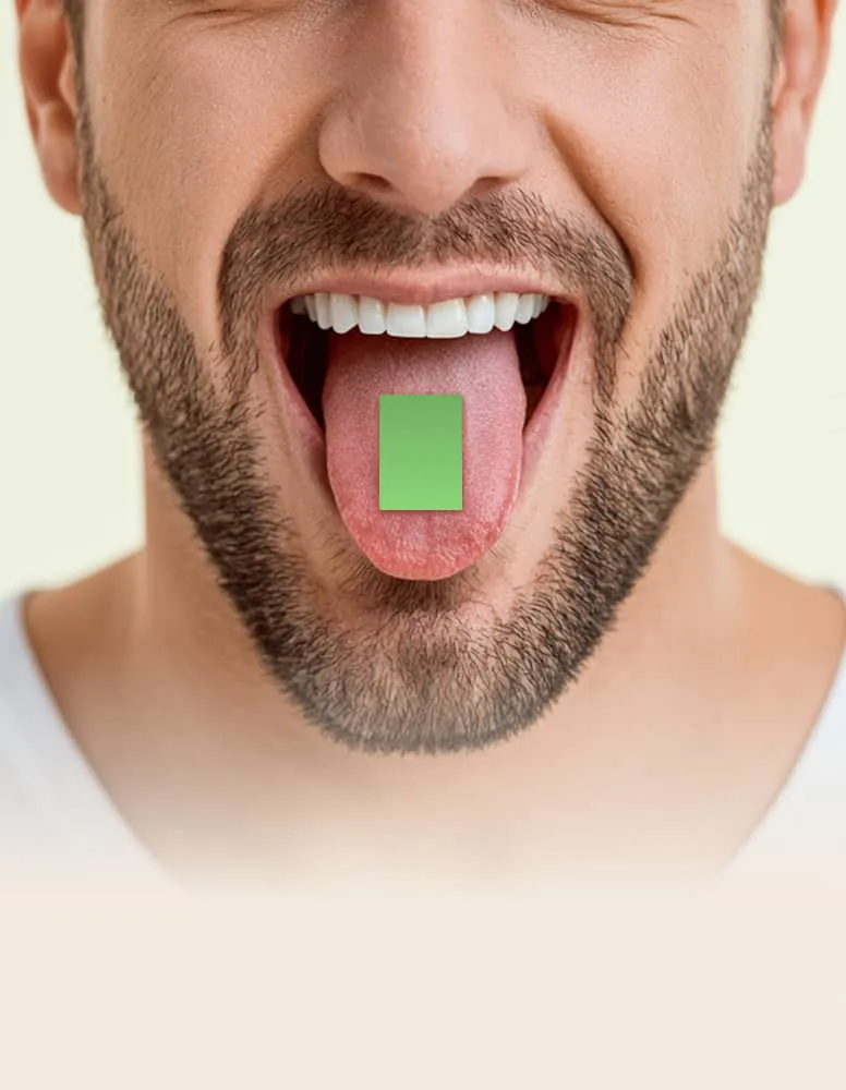 Man with beard shows tongue holding a small green rectangular tablet.