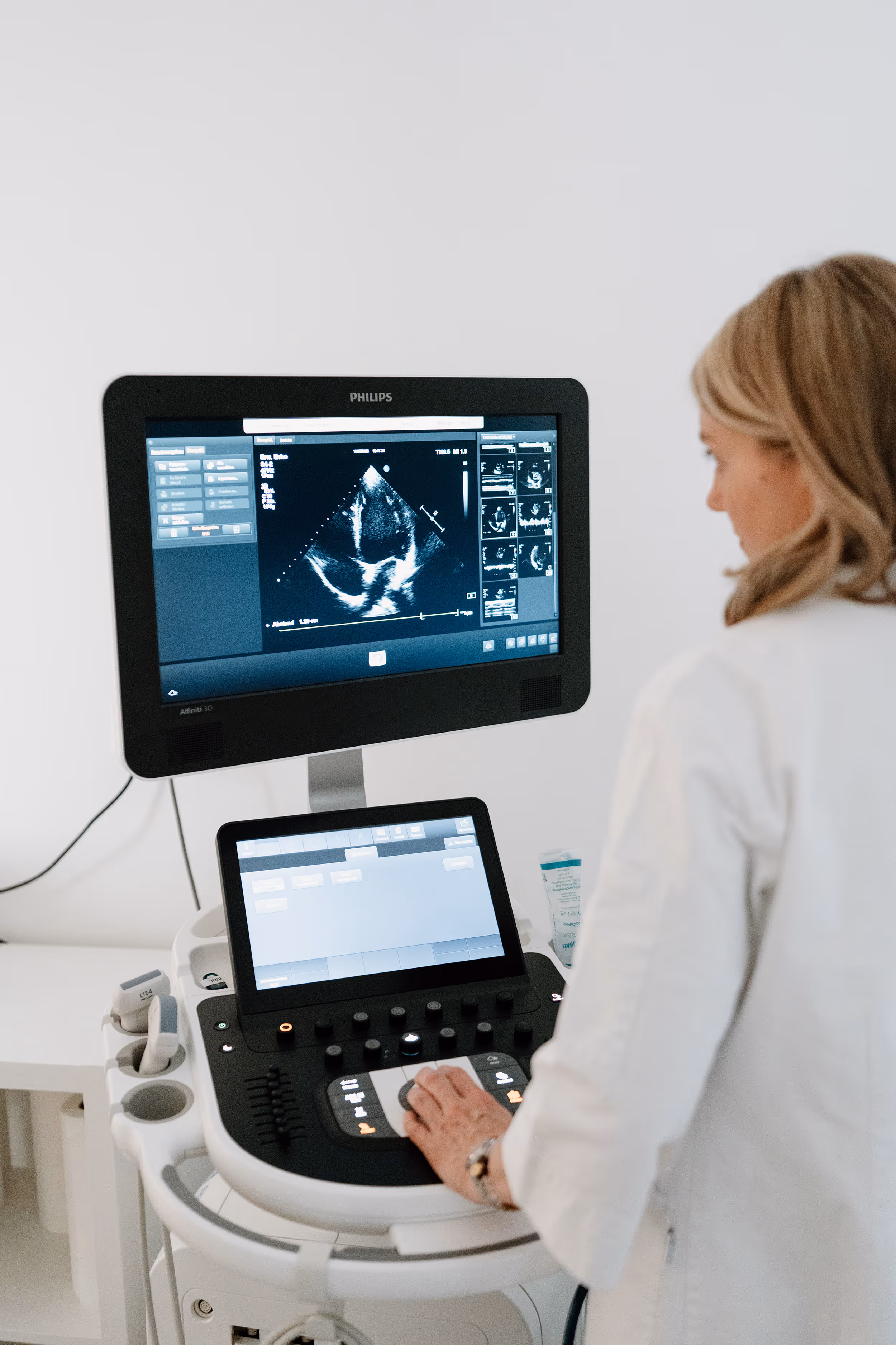 Ärztin bedient Ultraschallgerät mit Herzscan auf dem Bildschirm in einer medizinischen Praxis.