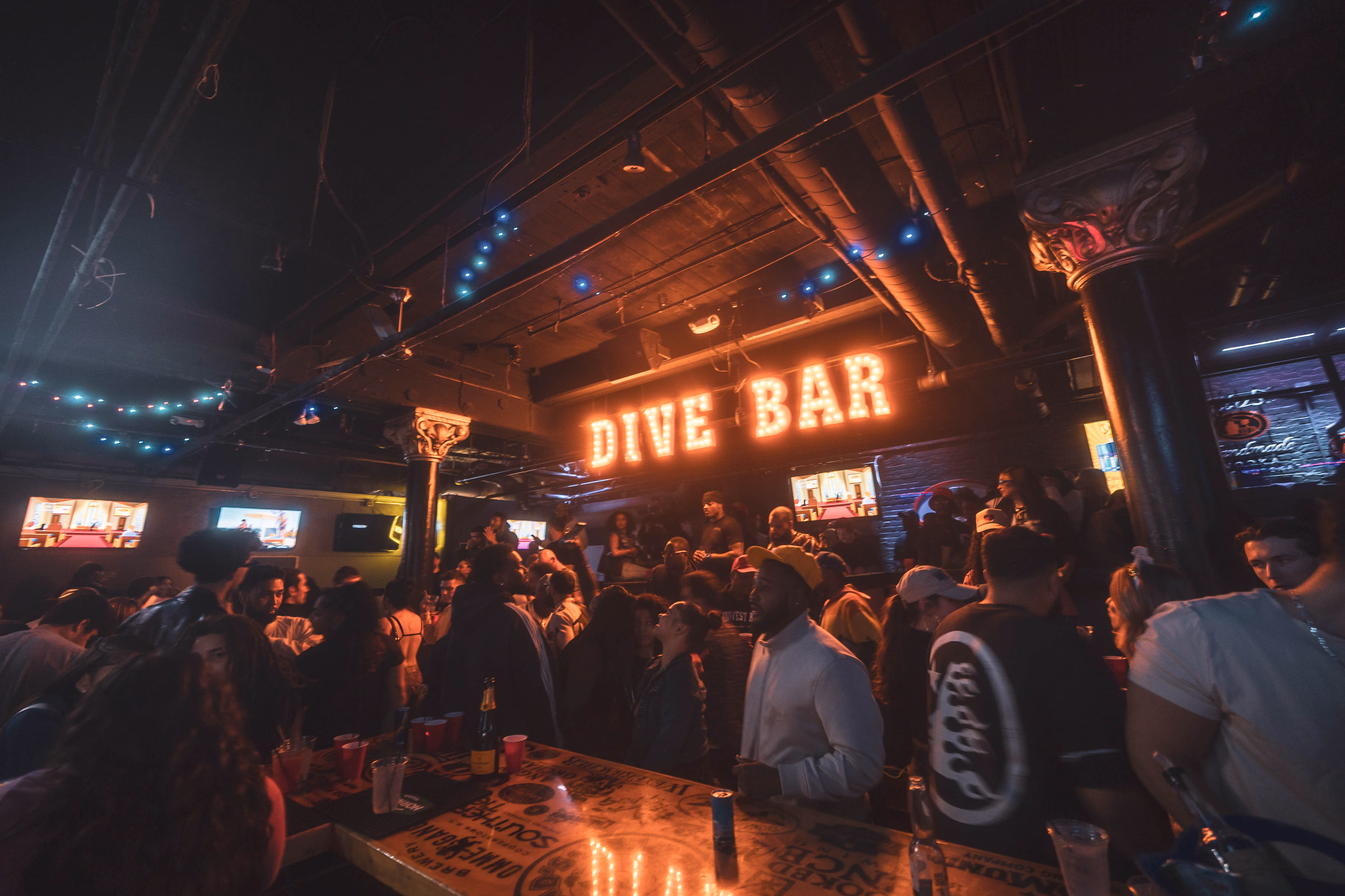 Crowd gathered beneath the glowing DIVE BAR sign during a busy night.