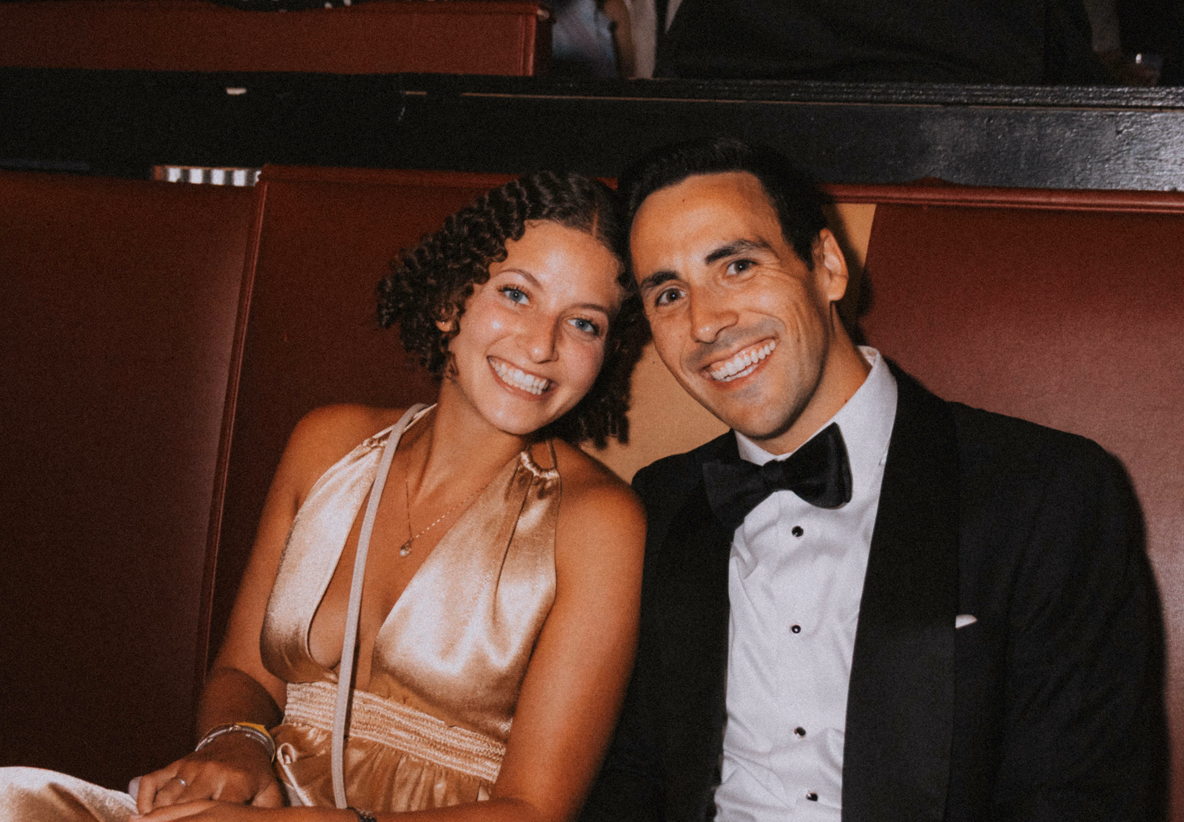 Couple in formal wear posing together in a red booth at Dive Bar Cleveland.
