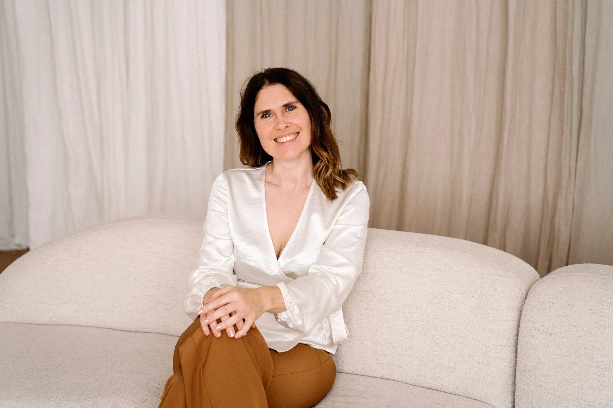Christina Stix-Pusswald lächelt auf einem beigen Sofa, Auftakt zu ihrem 4-Schritte-System für individuelles Webdesign