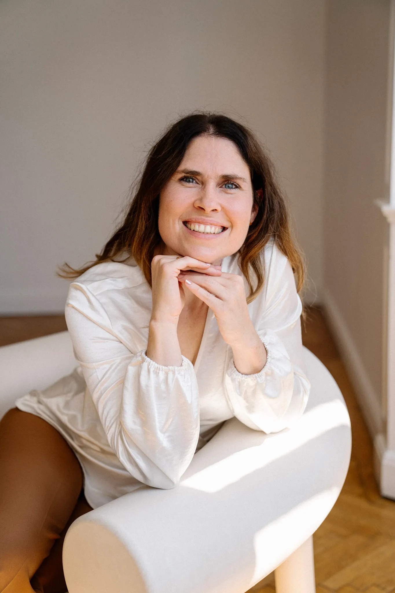 Christina Stix-Pusswald sitzt lächelnd auf einem cremefarbenen Sessel, bereit für Übergabe und Einschulung nach dem Launch