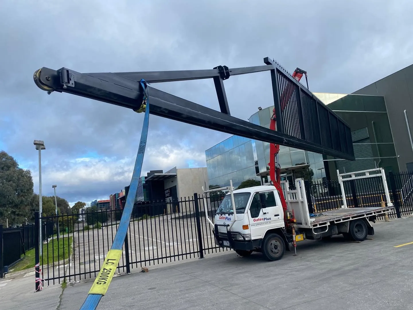 Large steel cantilever gate being positioned by crane during installation