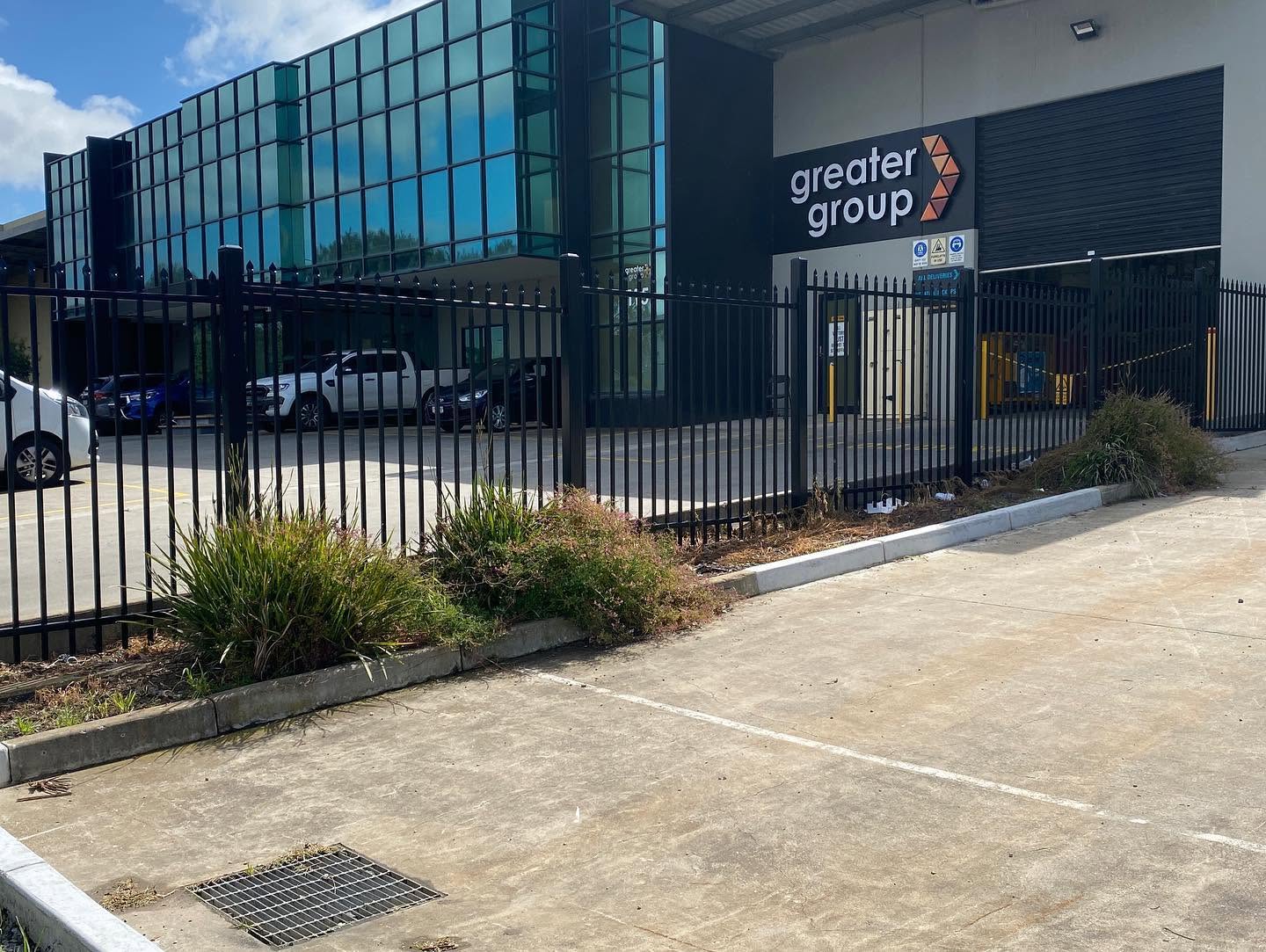 Completed black steel vehicle gate and secure commercial-site frontage