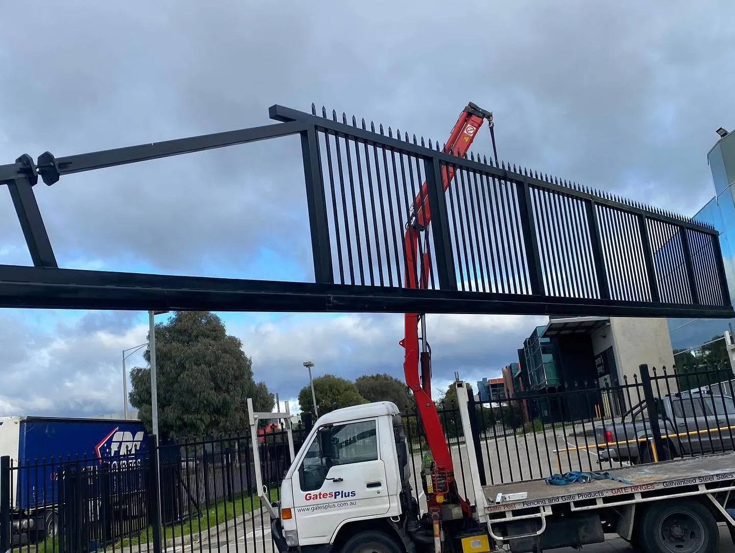 Large steel cantilever gate being positioned by crane during installation
