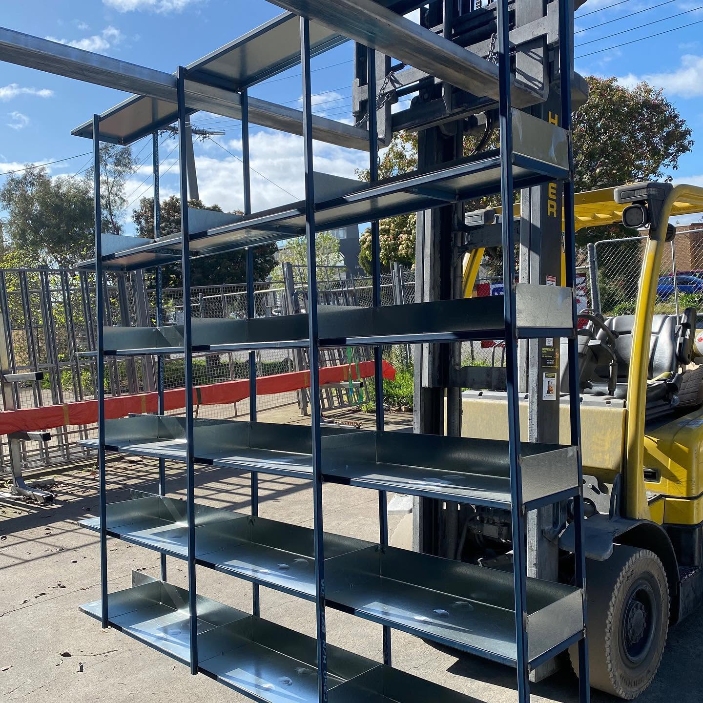 Fabricated metal frames and folded tray-style shelves being transported