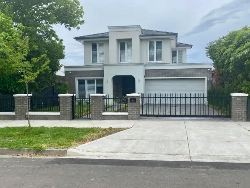 Completed residential frontage with black metal fencing, brick piers and light-coloured caps