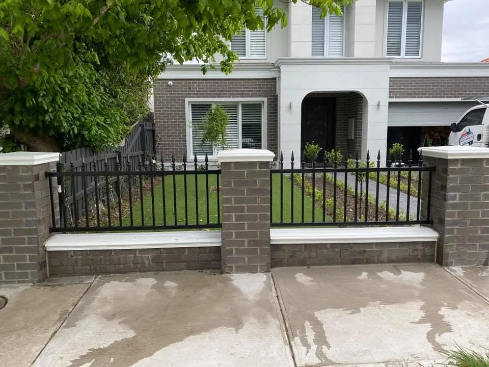 Completed residential frontage with black metal fencing, brick piers and light-coloured caps