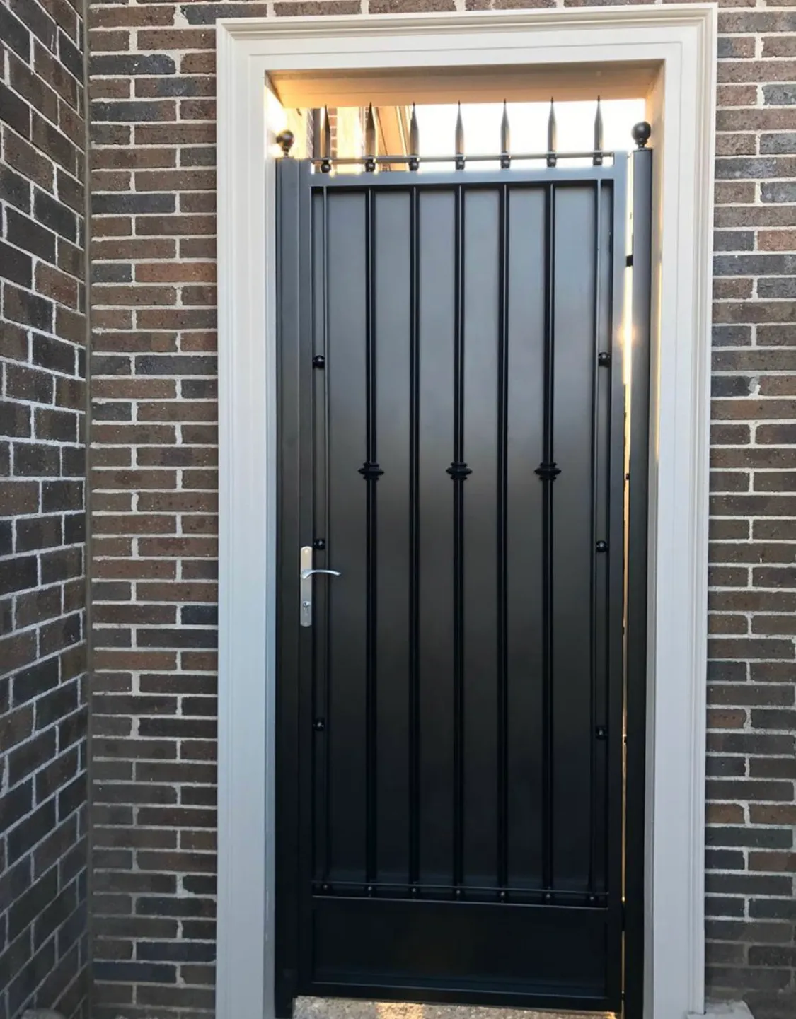 Custom solid privacy-panel door installed within a brick residential opening