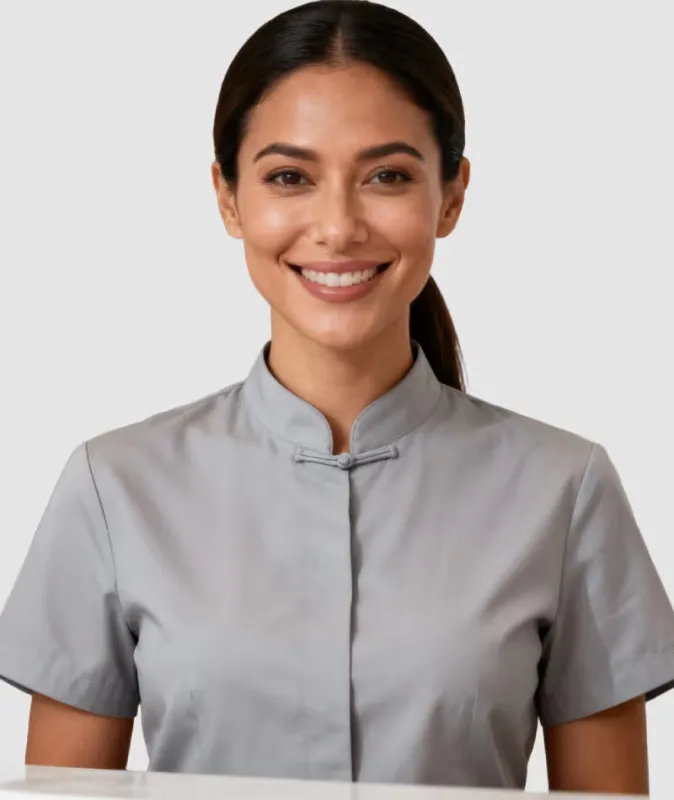 Smiling woman with dark hair in a gray Mandarin collar shirt against a plain background.