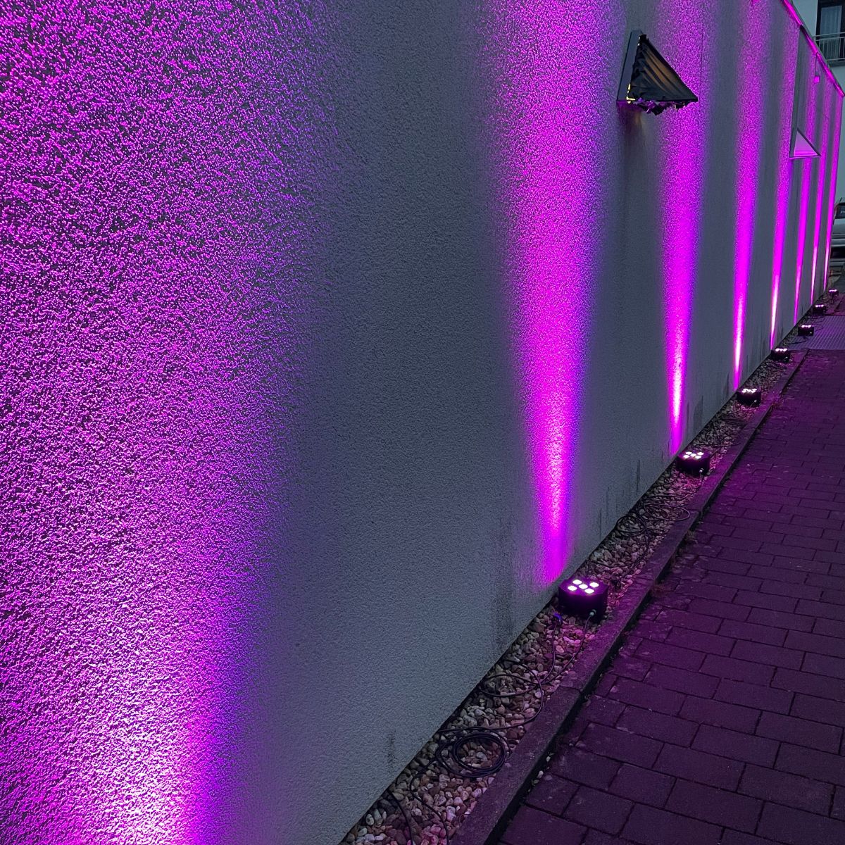 Mit lila Ambientebeleuchtung angestrahlte Wand in einer Eventlocation