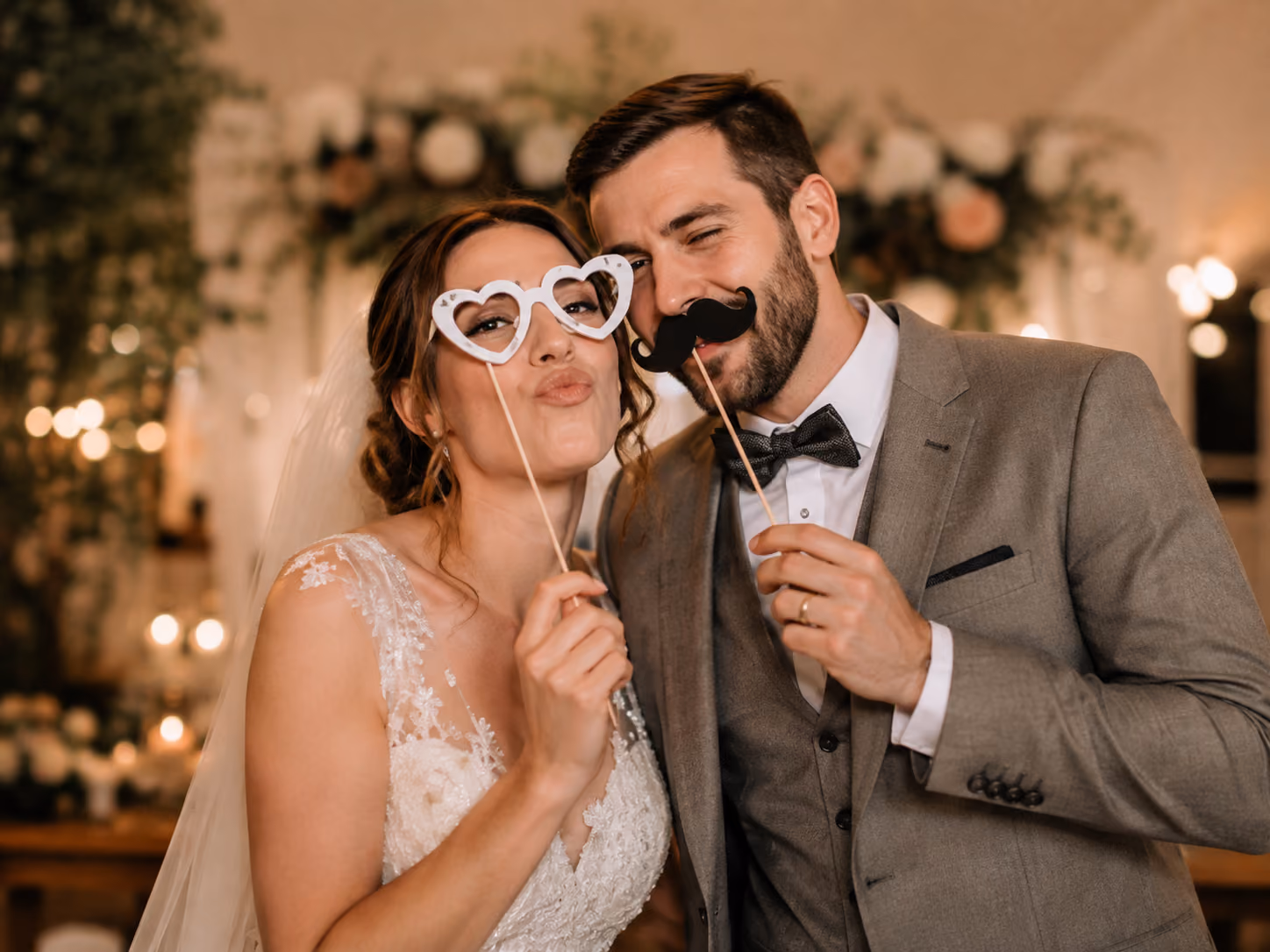 Brautpaar mit Fotobox-Requisiten auf einer Hochzeitsfeier
