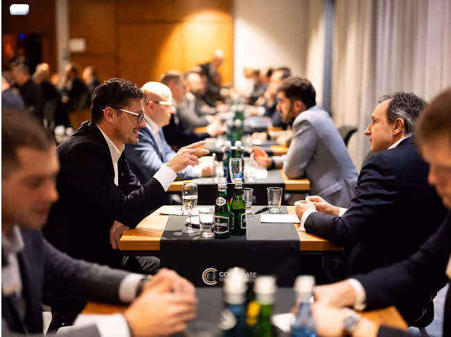 Members in one-on-ones along a long dining table at a CC US chapter meeting