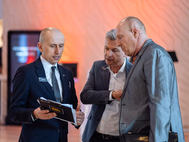 A CC US Director holding a folder, speaking with two members at a chapter event