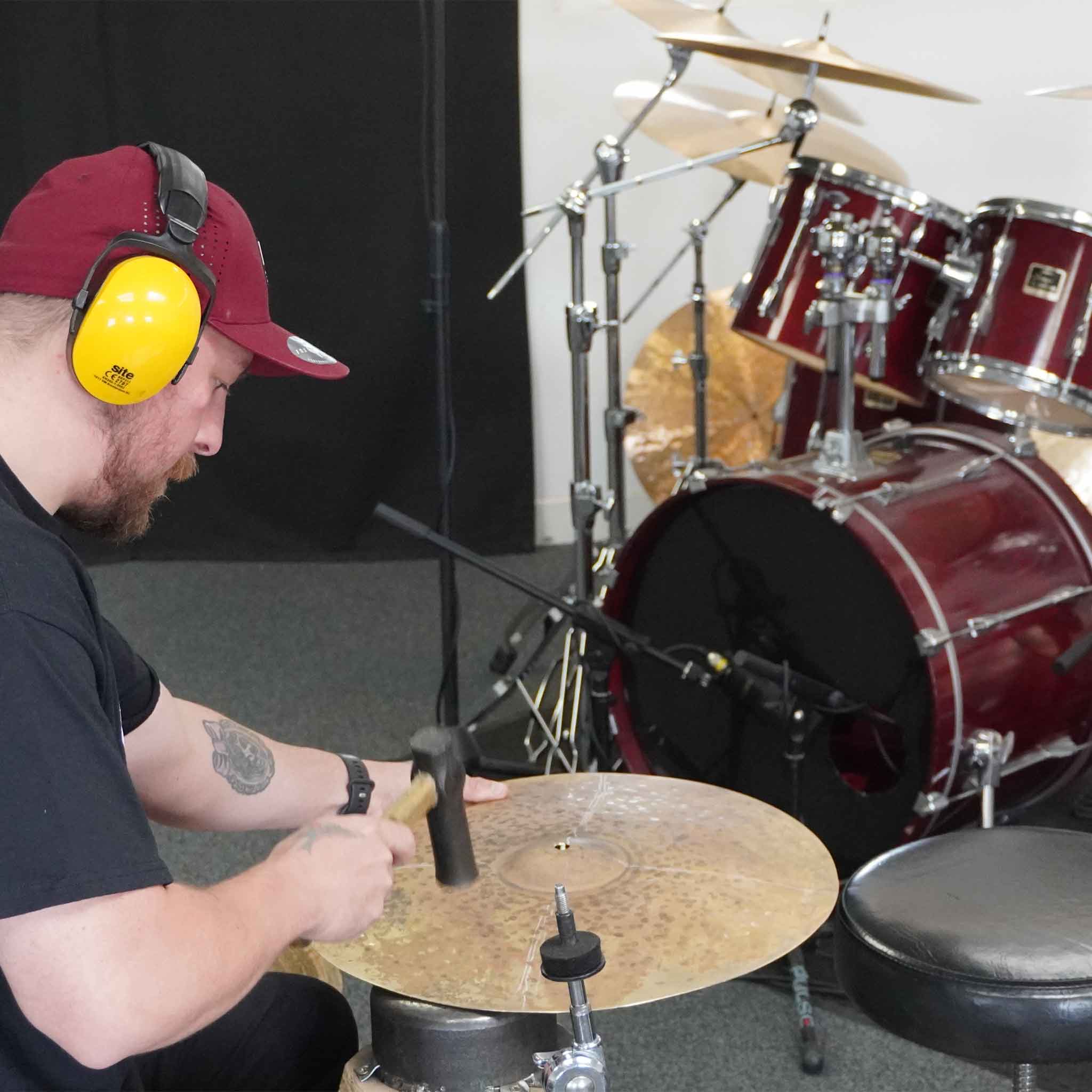 A drummer making his own cymbal by hand under the guidance of Dave Collingwood