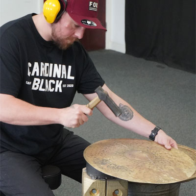 Hand hammering a cymbal at a Make Your Own Cymbal session in Bristol