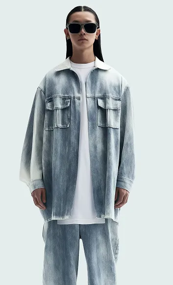 Model wearing oversized faded denim jacket and pants with black sunglasses and slicked-back hair.