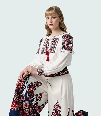 Woman wearing a white traditional embroidered blouse and skirt with red, blue, and black patterns.