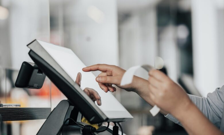 Hands using a touchscreen POS terminal while holding a printed receipt