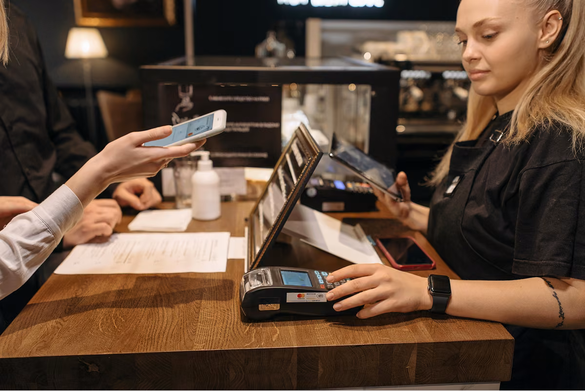 Customer making a contactless phone payment at a cafe card terminal