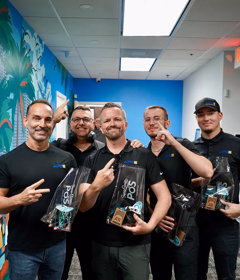 Team members in branded polos holding SuperSonic POS gift bags in the office
