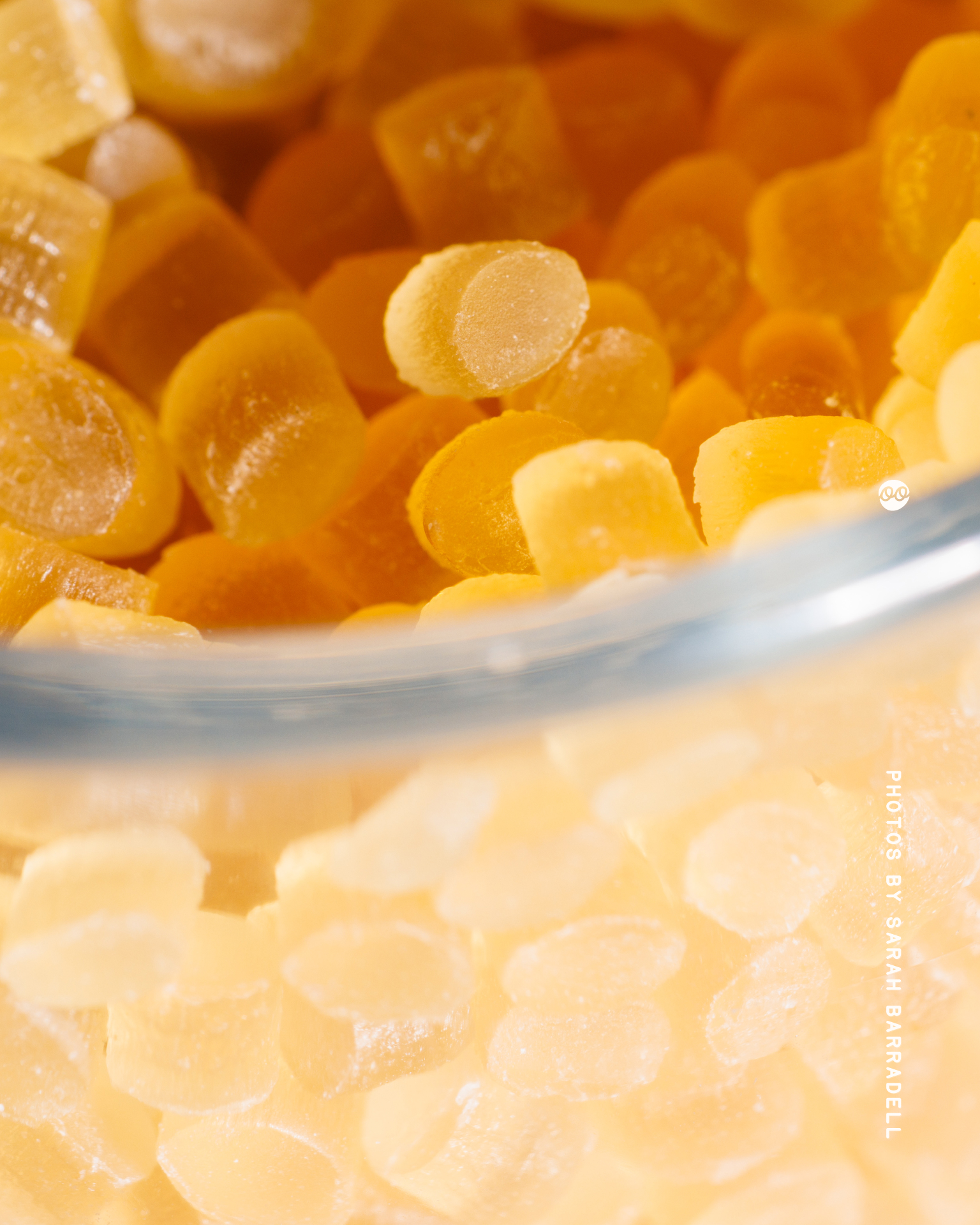 Close-up of small, smooth, yellow-orange plastic pellets inside a transparent container, with one pellet slightly elevated near the center.