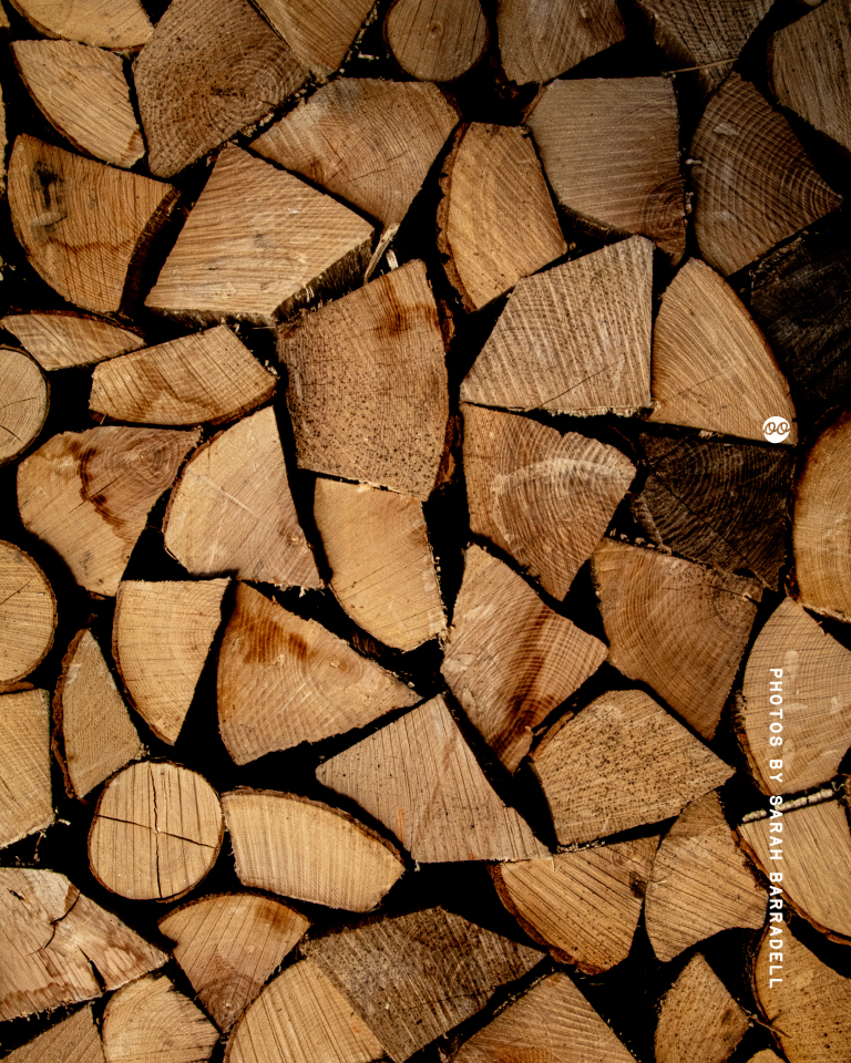 Close-up view of stacked firewood cut into various shapes and sizes, showing the wood grain and growth rings.
