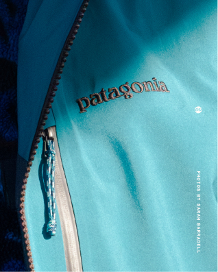 Close-up of a turquoise Patagonia jacket with a zippered pocket and the Patagonia logo embroidered on the fabric.