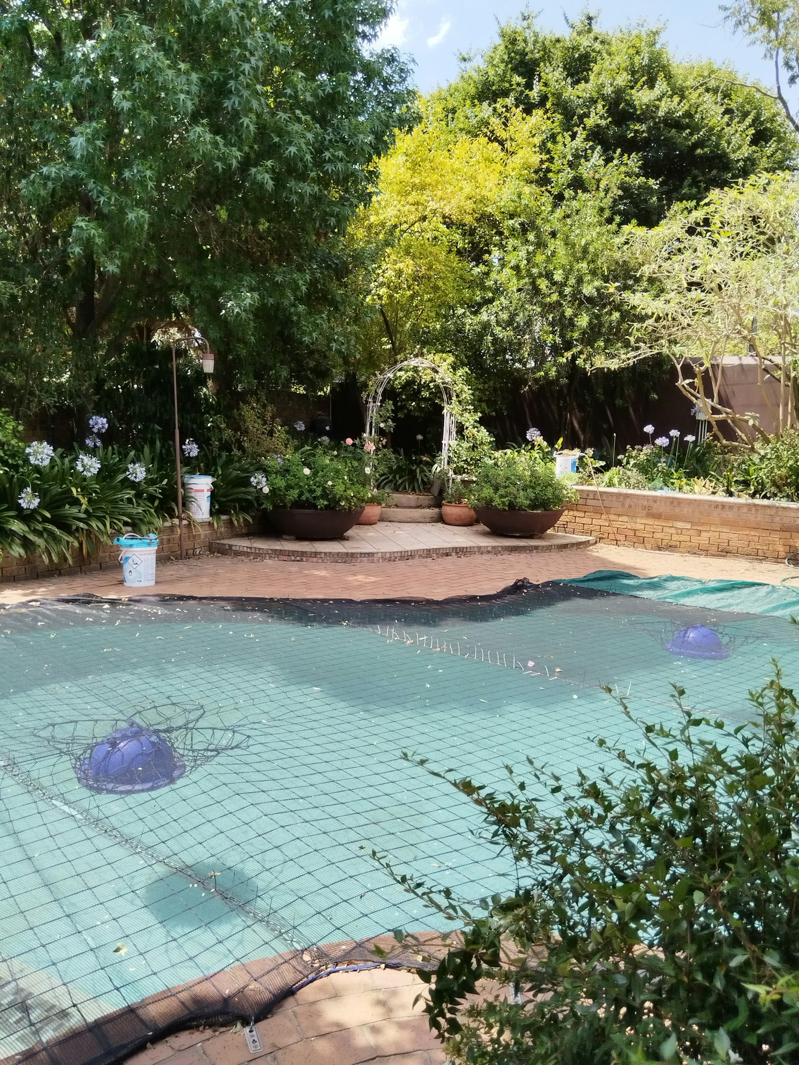 Residential backyard pool secured with a safety cover for winter closing