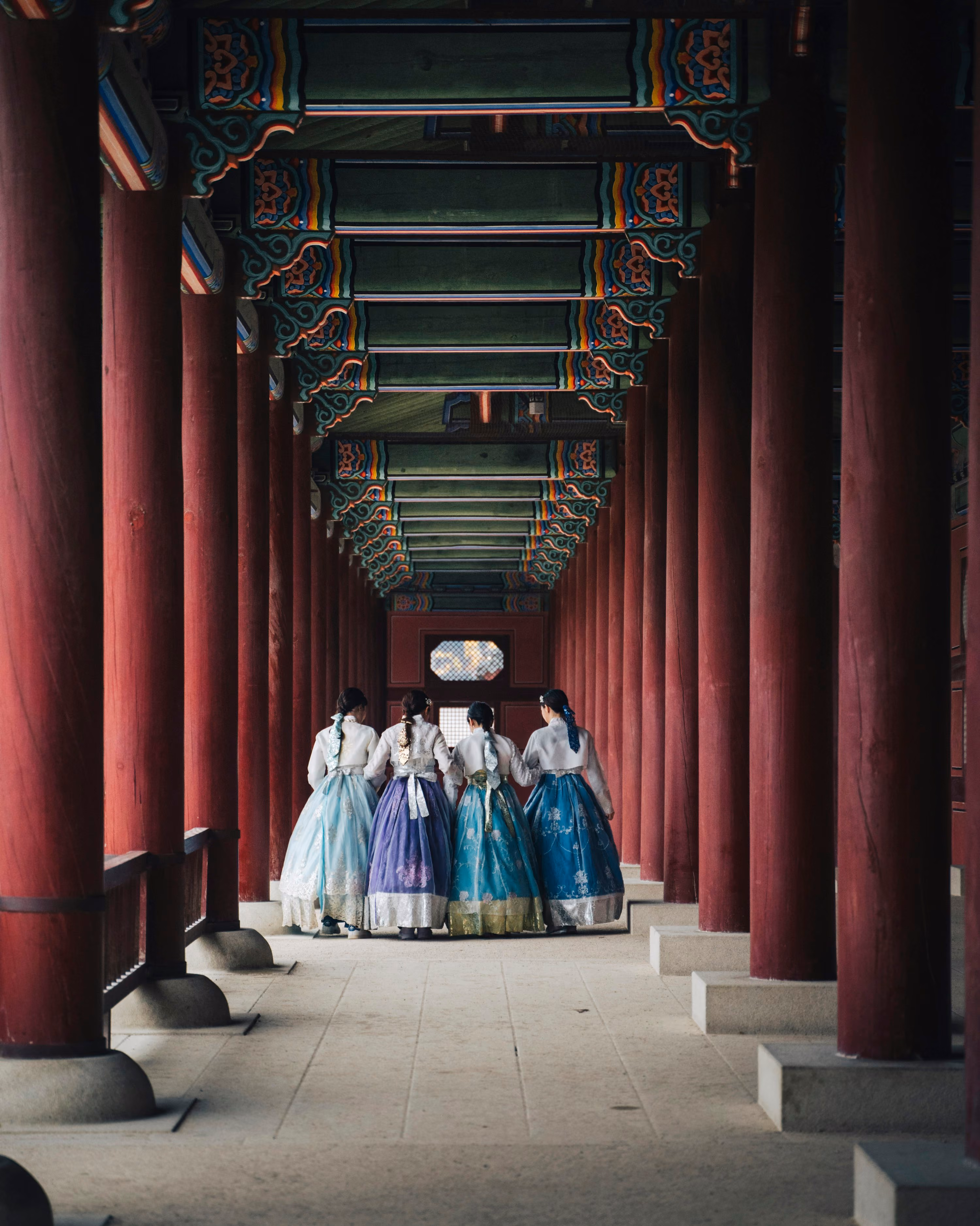 Grupo de mujeres con hanbok tradicional coreano paseando por un pasillo de palacio en Seúl