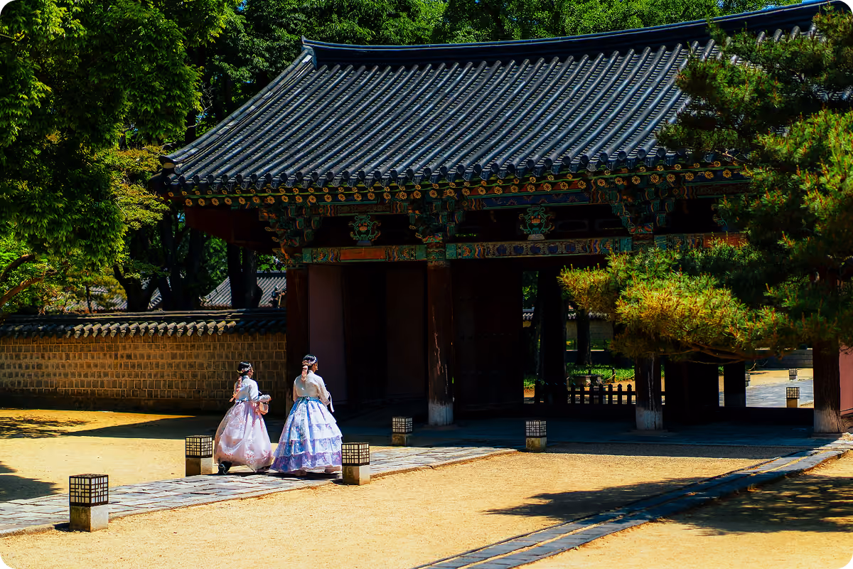 Dos mujeres vestidas con hanbok tradicional junto a la puerta de un templo coreano