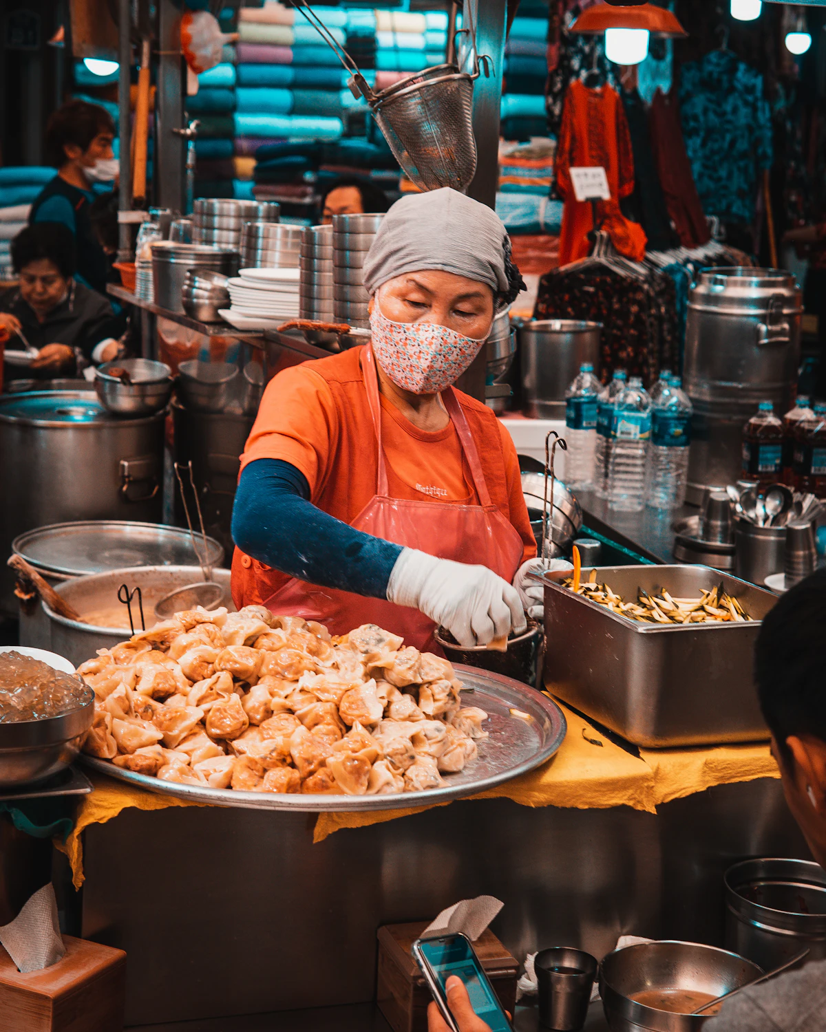 Hombre sirviendo un cuenco de comida callejera coreana en un puesto del mercado Gwangjang